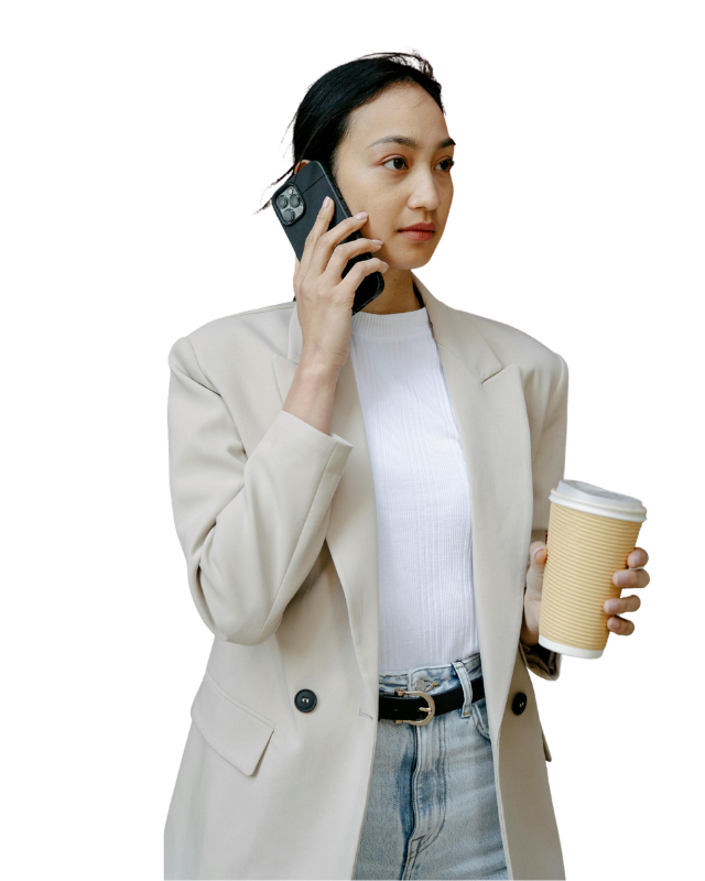 A professional woman with black hair tied back, wearing a beige oversized blazer over a white ribbed top and light-wash jeans with a black belt.